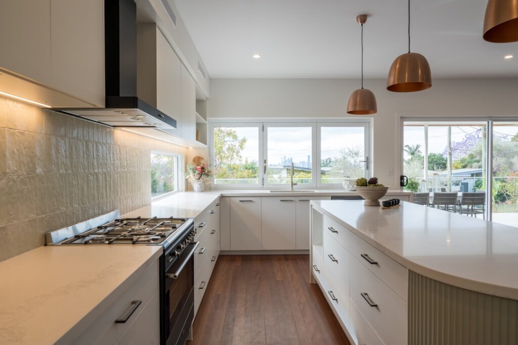 Bright and airy minimalist kitchen with clean countertops and natural light streaming through a window, creating a serene ...