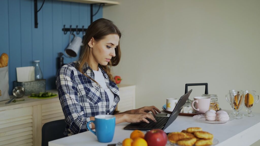Modern laptop open on a clean kitchen counter, the screen displaying dozens of overlapping browser tabs, symbolizing digit...
