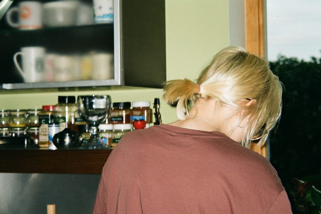 Woman peacefully sipping coffee in a bright kitchen as the morning sun streams through the window, symbolizing a calm star...