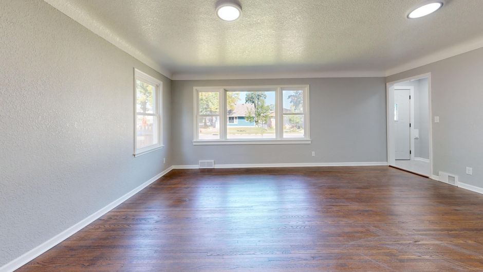 A minimalist and serene living room interior with comfortable furniture bathed in natural light from large windows, creating a quiet sanctuary.